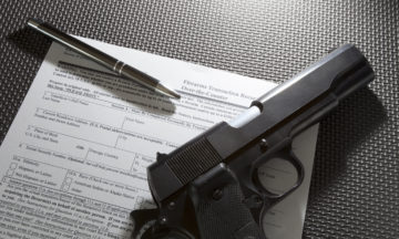Handgun and pen and paperwork required for the background check for a gun purchase