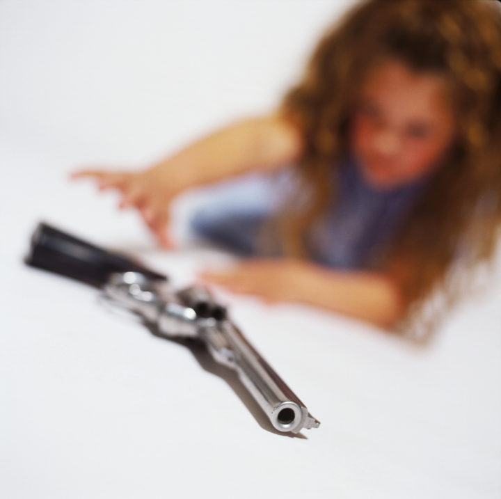 blurred view of a young girl (6-8) trying to pick up pistol