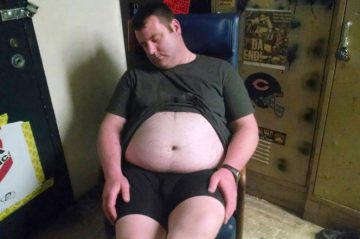 drunk man with large belly passed out in a chair in a locker room