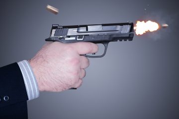 hand firing a handgun with bullet casing shooting out and flash