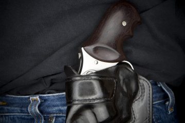 Stainless Steel .357 revolver in a black leather holster on a man's side.