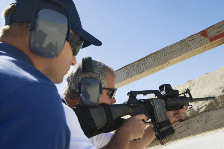 Instructor with man aiming machine gun at firing range