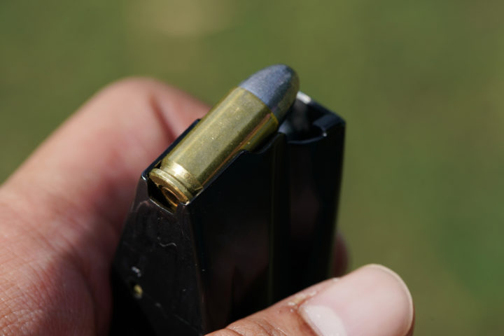 close-up on hand loading 9mm bullets into the gun magazine