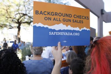 Hand holding a sign supporting Nevada's background check law