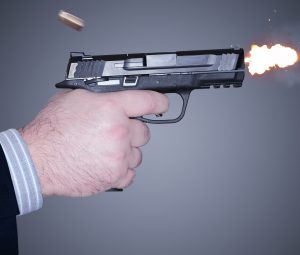 hand firing a handgun with bullet casing shooting out and flash