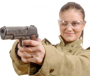 woman wearing goggles with one eye closed aiming a handgun