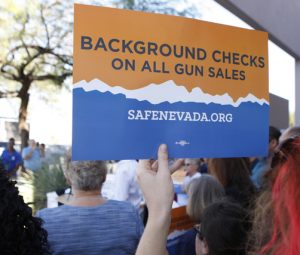 Hand holding a sign supporting Nevada's background check law