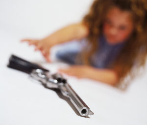 blurred view of a young girl (6-8) trying to pick up pistol