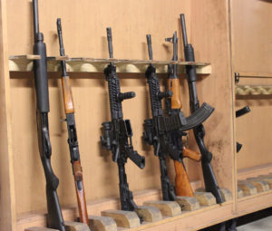 gun rack holding assorted rifles and semi-automatic weapons