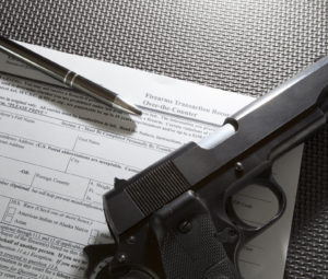 Handgun and pen and paperwork required for the background check for a gun purchase