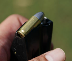 close-up on hand loading 9mm bullets into the gun magazine