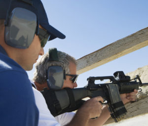 Instructor with man aiming machine gun at firing range